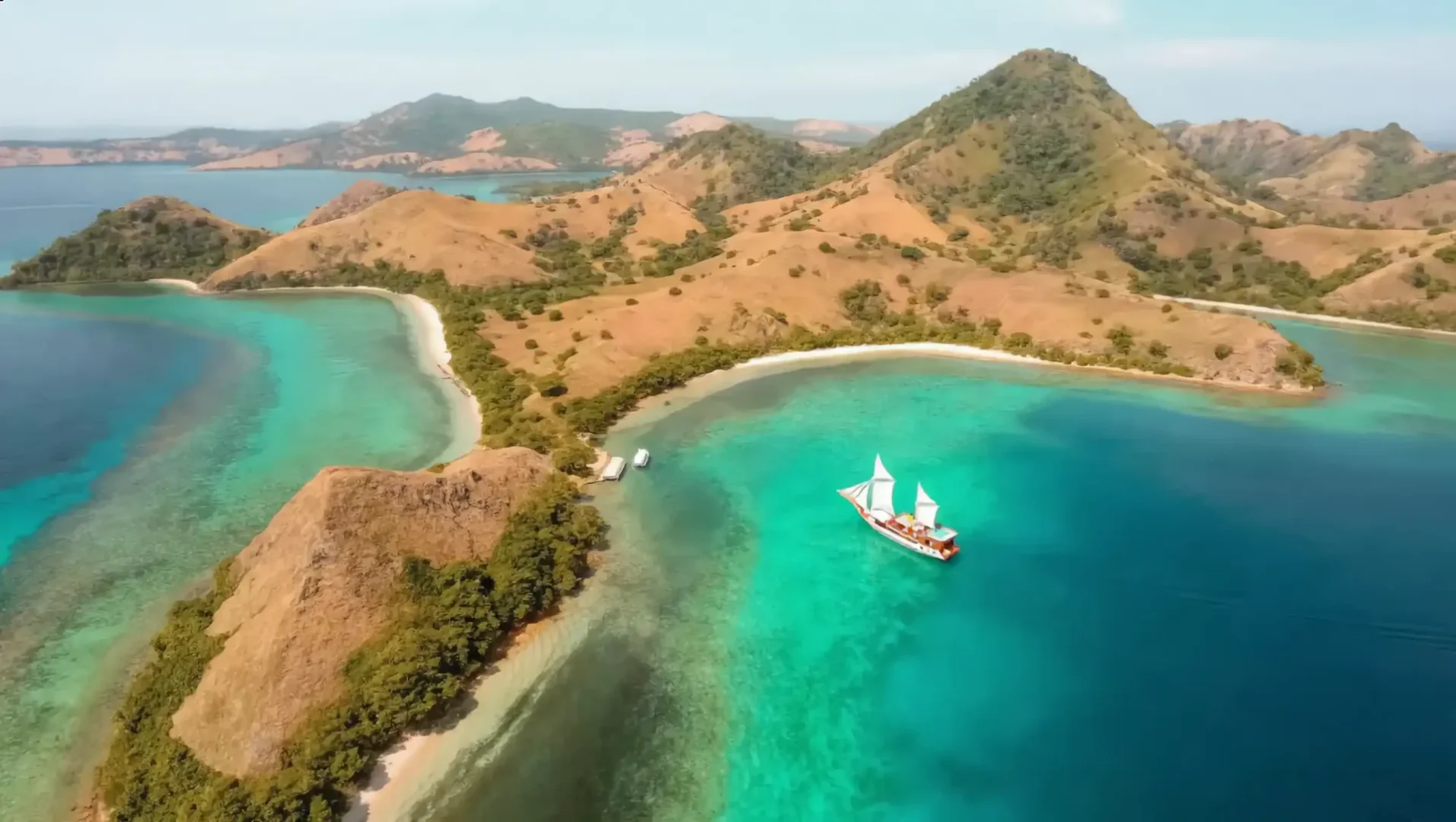 Aerial view of a phinisi in a turquoise bay, Komodo