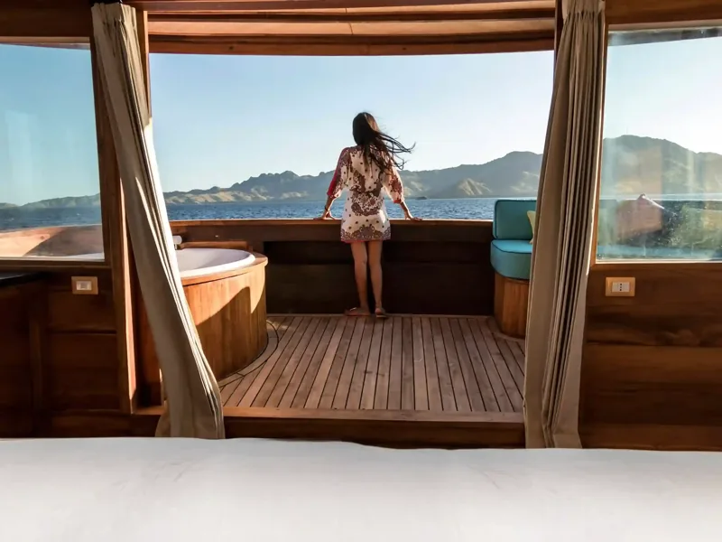 Guest looking out of a cabin window at the Komodo coastline