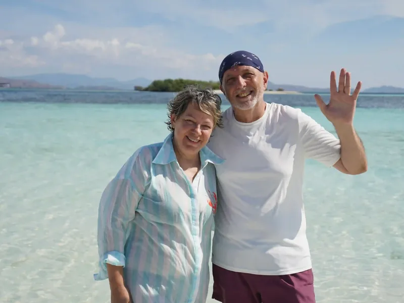 Couple waving in the shallows of a Komodo beach