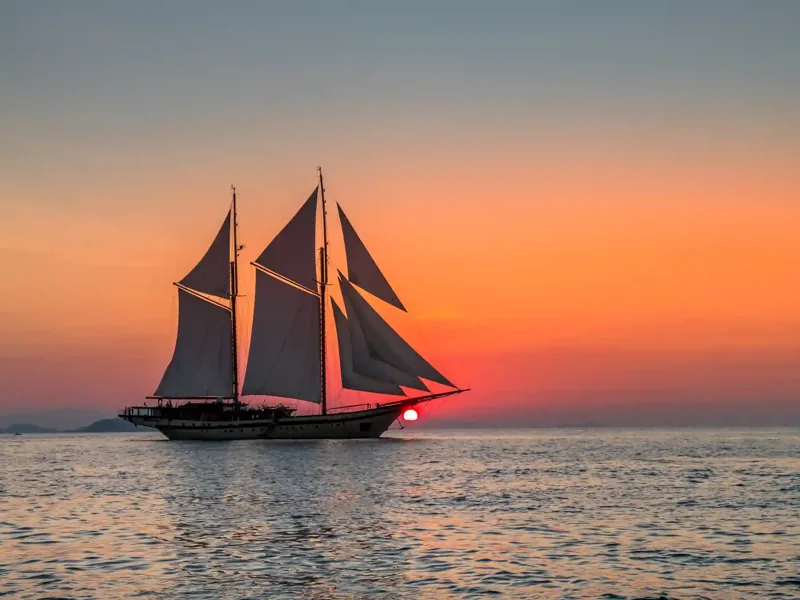 Silhouette of a phinisi at sunset in the Komodo archipelago