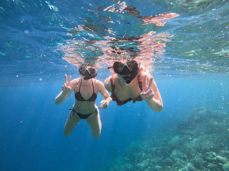Two snorkelers at the surface above a Komodo reef